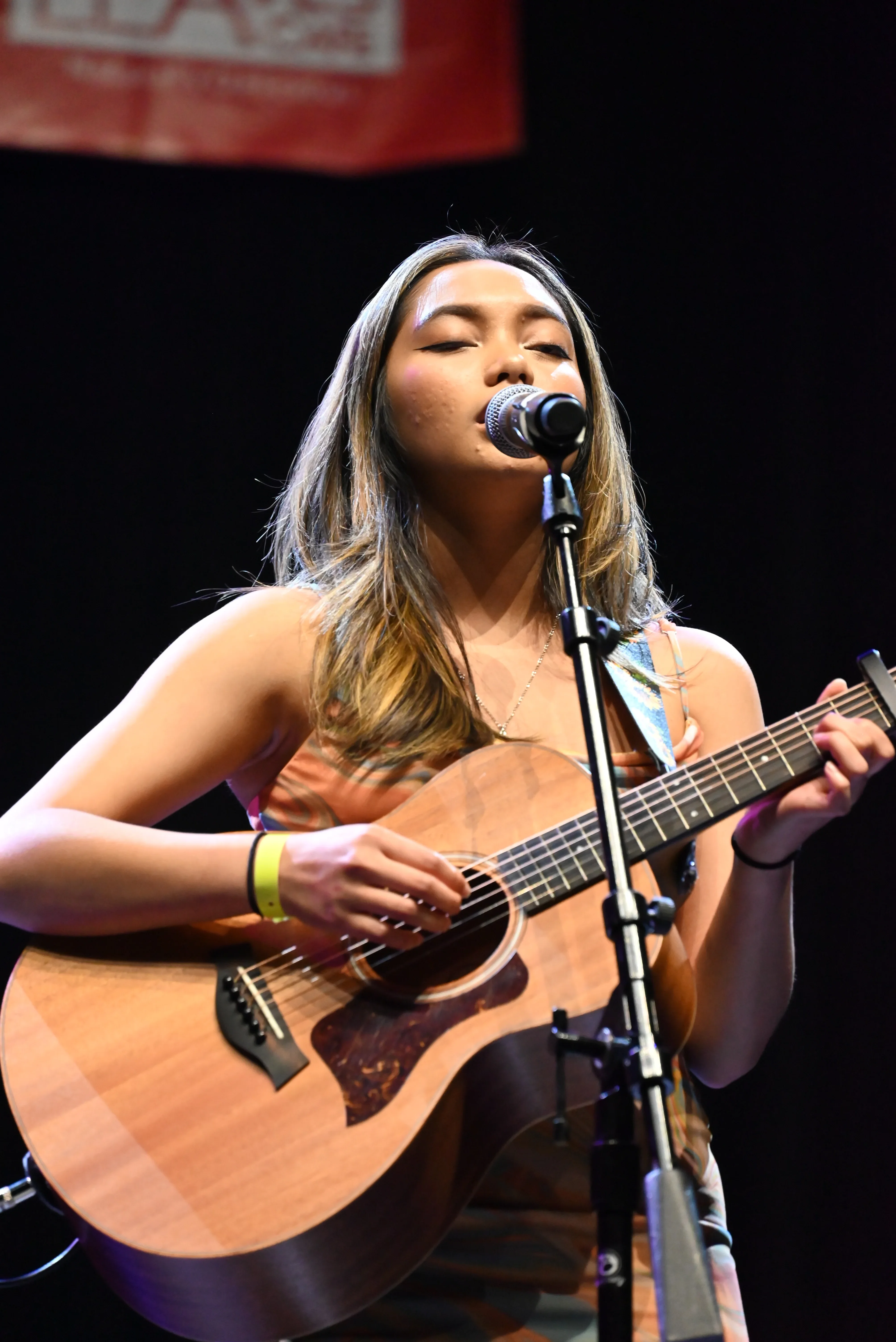 Female artist playing acoustic guitar on stage