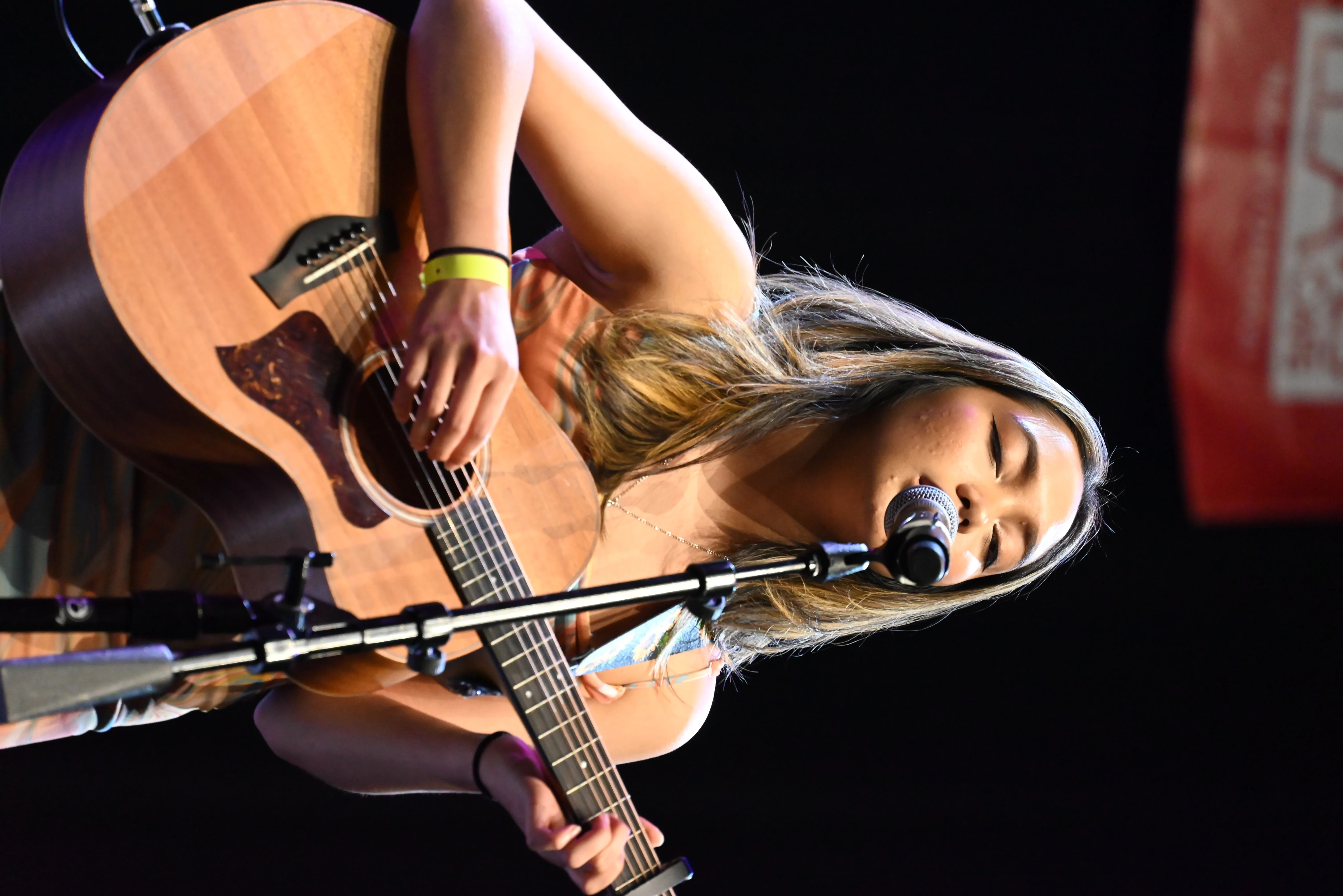 Female artist playing acoustic guitar on stage