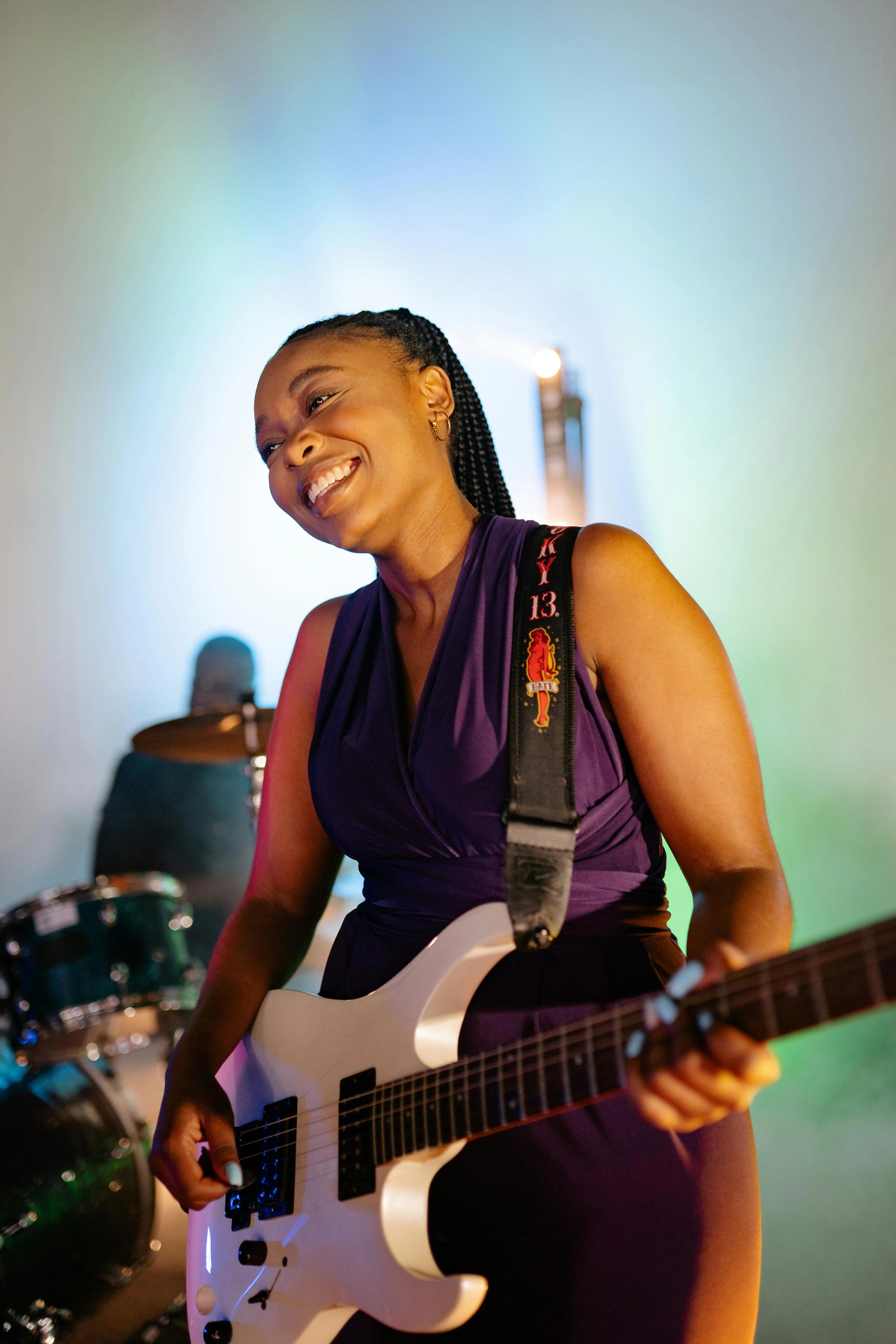 Female guitarist on stage, purple dress, indoor venue